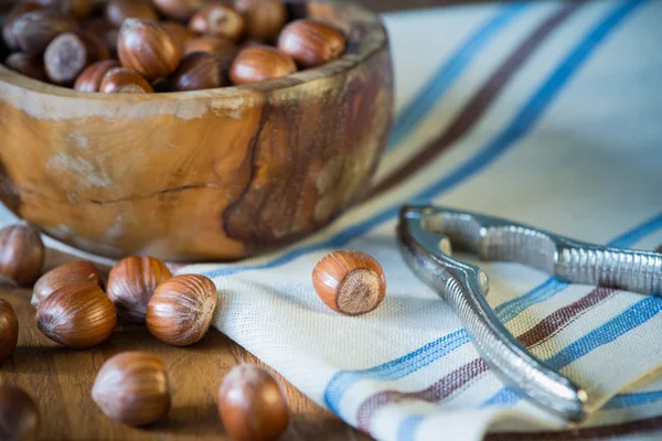Hazelnuts in bowl and nut cracker on cloth — Stock Photo, Image