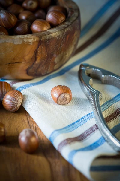 Hazelnuts in bowl and nut cracker on cloth — Stock Photo, Image