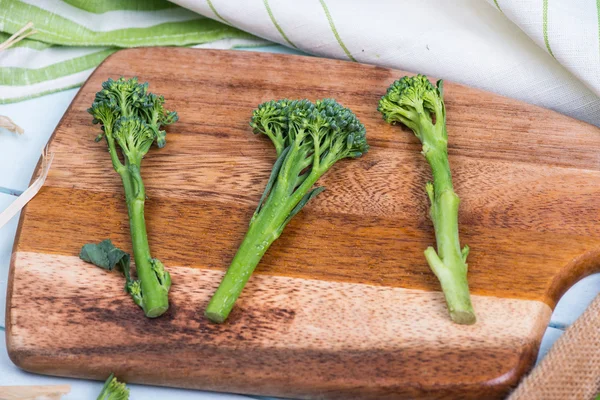 Fresh green broccolini on clipping board — Stock Photo, Image