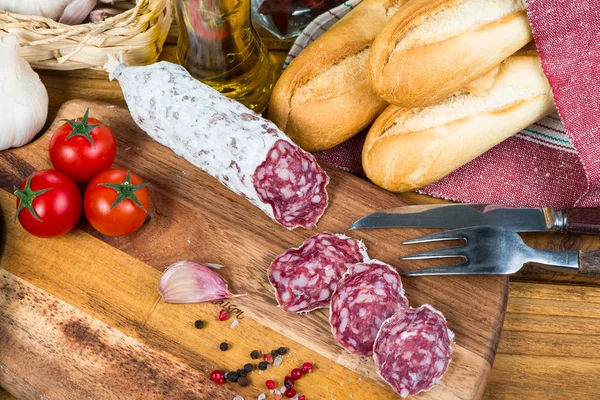 Overhead view on sliced salami and herbs on wooden board — Stock Photo, Image