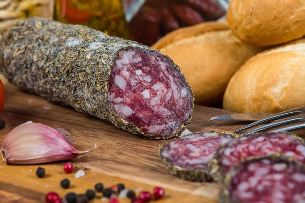 Traditional salami with herbs on wooden board — Stock Photo, Image