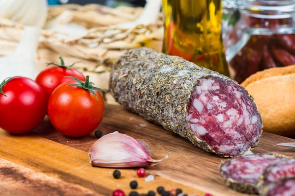 Traditional salami with herbs on wooden board and olive oil — Stock Photo, Image