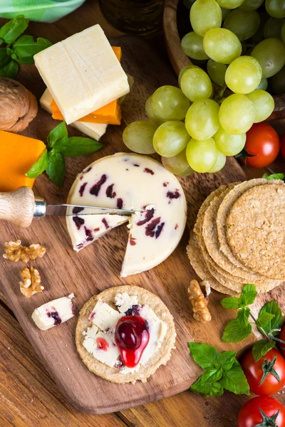 Top overhead view on cheese board with grape oat cakes and cranb — Stock Photo, Image