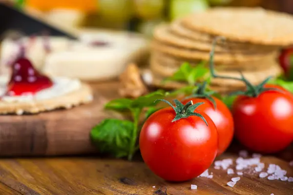 Tomatoes with oat cakes and cheese in background — Stock Photo, Image
