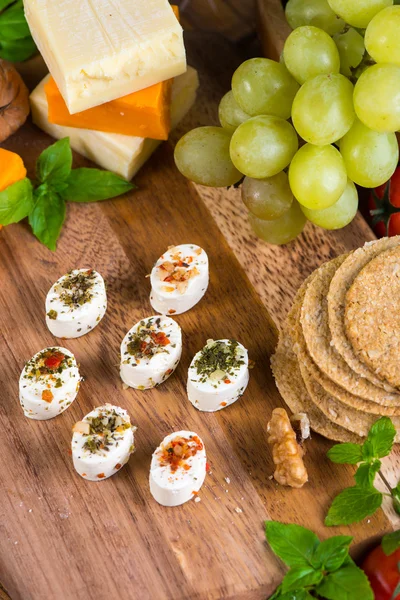 Selection of party cheese snacks with herbs on board — Stock Photo, Image