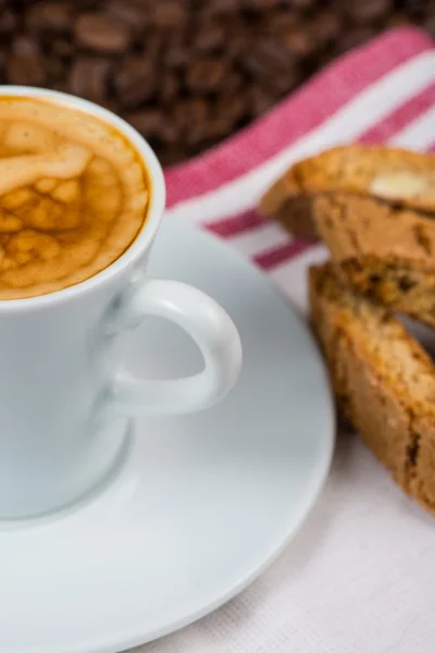 Tasse cremiger Expresso über gerösteten Kaffeebohnen und italienischem Bbis — Stockfoto