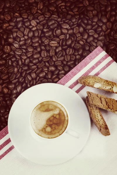 Taza de expresso cremoso sobre granos de café tostados y bis italianos — Foto de Stock