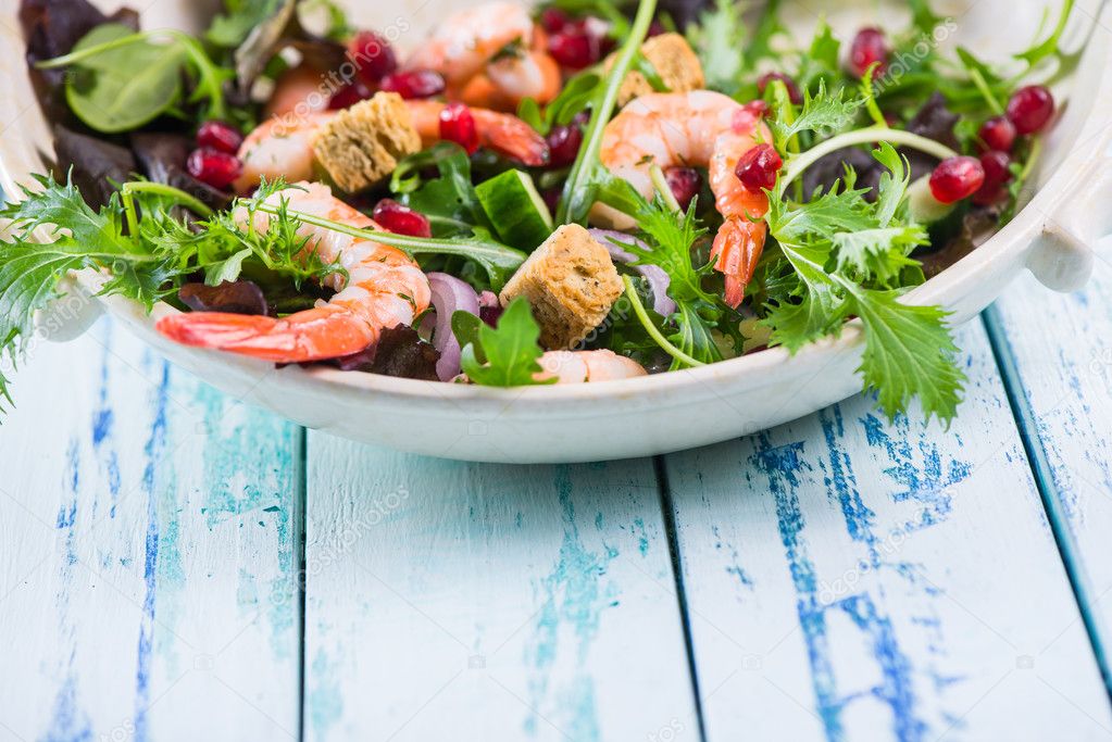 Healthy salad with seafood and pomegranade in rustic bowl