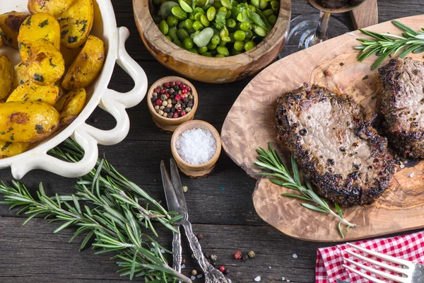 Bife de carne rara médio grelhado com ervas na mesa rústica — Fotografia de Stock