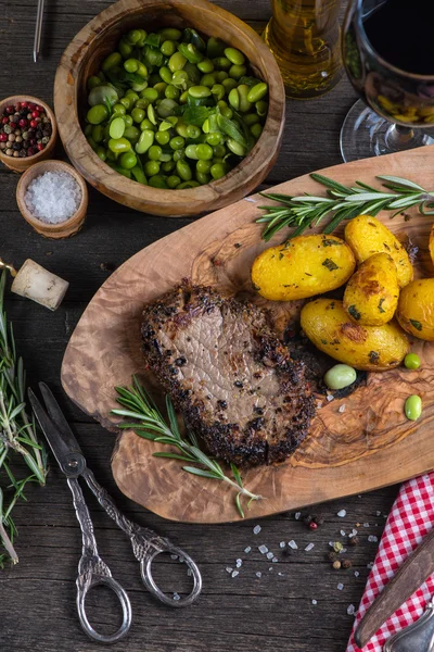 Sığır eti biftek ile kızarmış patates ve otlar, üstten görünüm — Stok fotoğraf