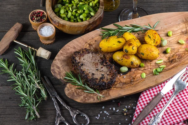 Beef steak with roasted potatoes in rustic kitchen — Stock Photo, Image