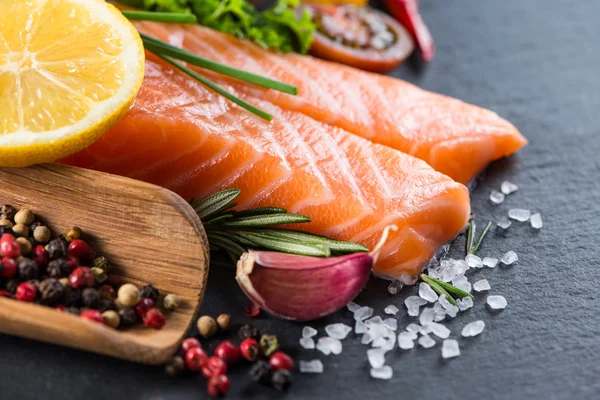 Portion of fresh salmon and herbs on black background — Stock Photo, Image