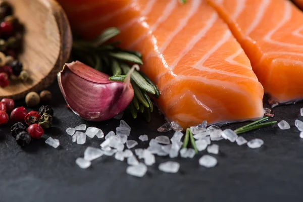 Portion of fresh salmon and herbs on black background — Stock Photo, Image