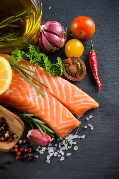 Portion of fresh salmon with spices,herbs and vegetables on blac — Stock Photo, Image