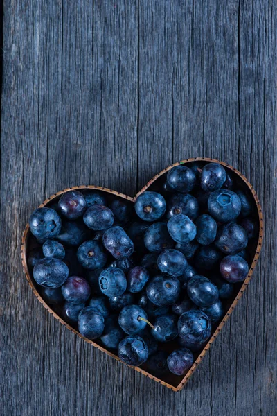 Fruit heart shape of blueberries from above on wooden background — Stock Photo, Image