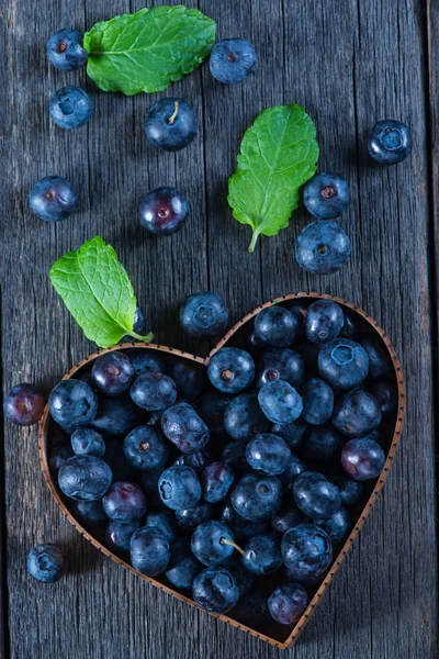 Fruit heart shape of blueberries from above on wooden background — Stock Photo, Image