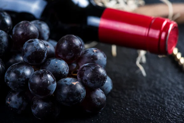 Garrafa de vinho tinto com uvas e saca-rolhas — Fotografia de Stock