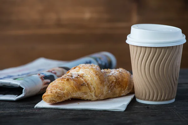 Koffie en verse croissants en krant weg te nemen — Stockfoto