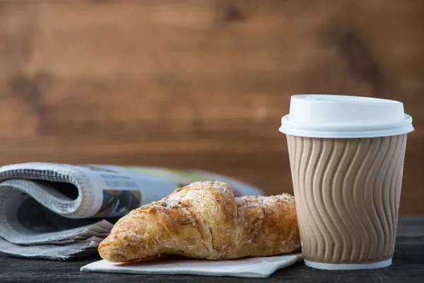 Kaffee und frisches Croissant und Zeitung zum Mitnehmen — Stockfoto