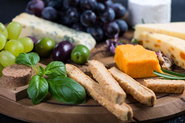 Tábua de queijo com uvas frescas, ervas e azeitonas — Fotografia de Stock