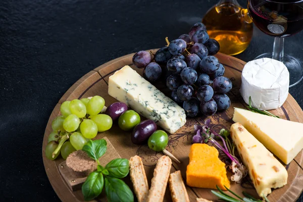 Tábua de queijo com uvas frescas, ervas e azeitonas — Fotografia de Stock