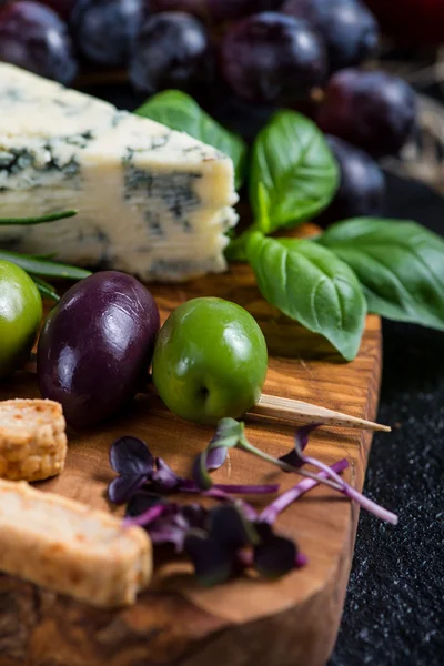 Food background,rustic board with cheese herbs and grapes — Stock Photo, Image