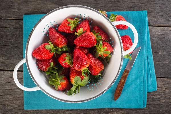 新鲜的草莓，在质朴漏勺木制的桌子上 — 图库照片