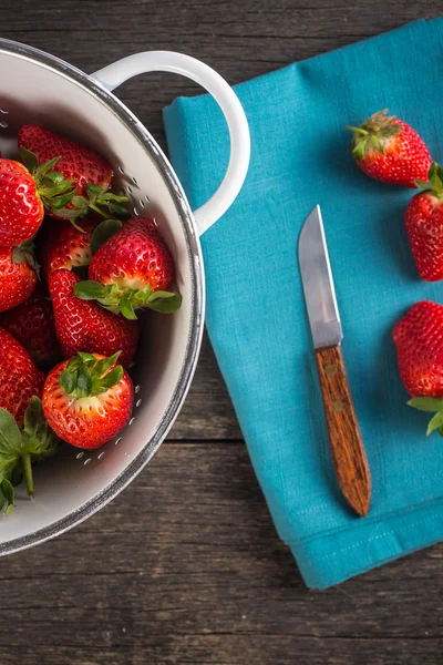 Verse aardbeien in rustieke vergiet op houten tafel — Stockfoto