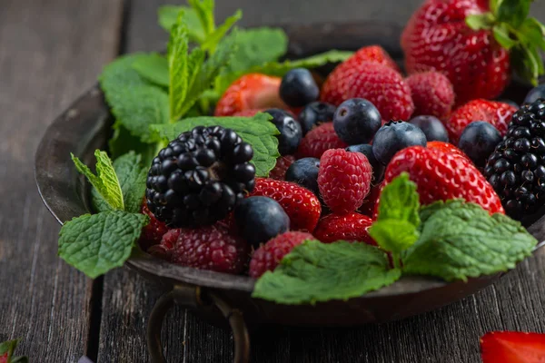 Fresh summer berries with mint in rustic bowl Stock Picture