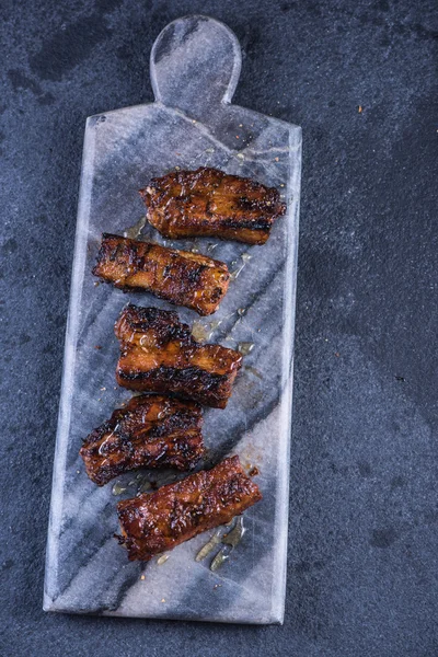 Krokante varkensvlees belly segmenten op graniet bord — Stockfoto