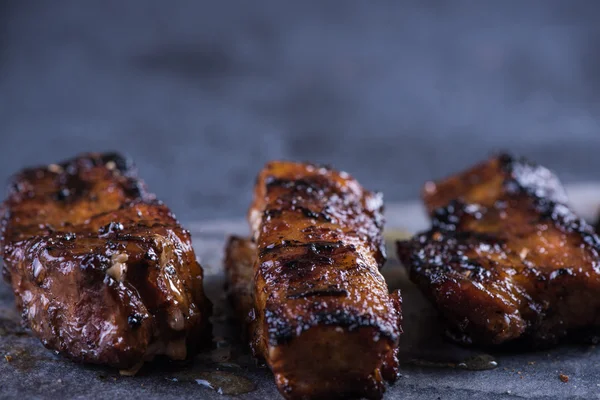 Rodajas de panceta de cerdo a la parrilla sobre tabla de mármol y fondo de pizarra —  Fotos de Stock