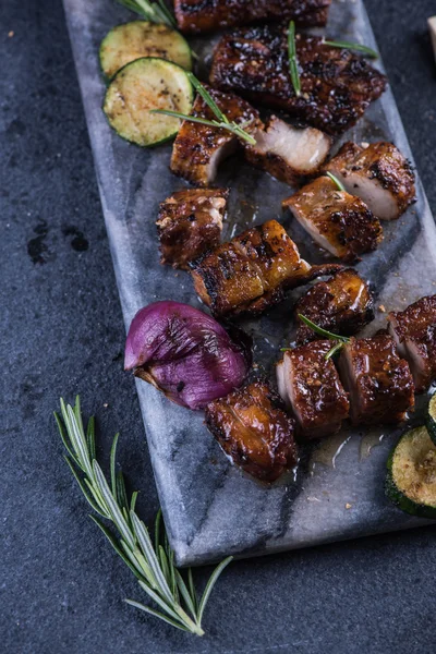 Grilled pork belly slices on marble board and veggies from above — Stock Photo, Image
