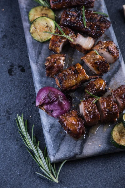 Gegrillte Schweinebauch-Scheiben auf Marmorplatte und Gemüse von oben — Stockfoto