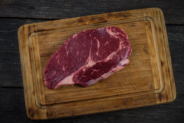 Nyers ribeye marha steak fejük fölött a fa rusztikus board — Stock Fotó