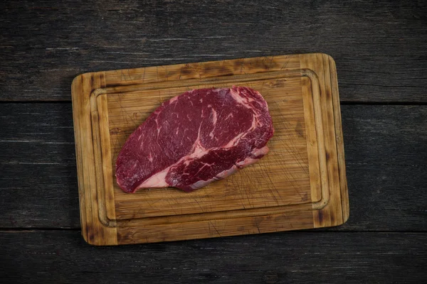 Ruwe ribeye biefstuk overhead op houten rustieke bord — Stockfoto
