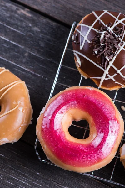 Hand decorated artisan donuts on wooden table — Stock Photo, Image