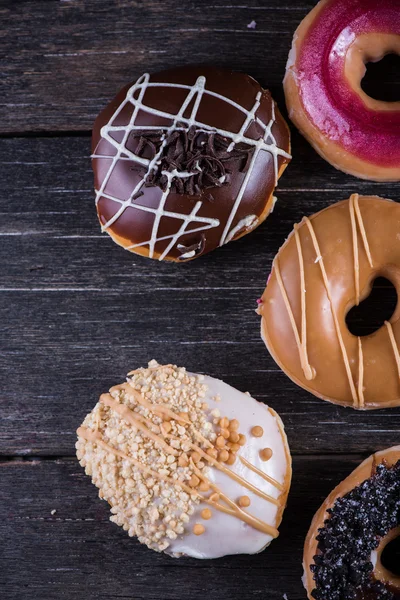 Hand decorated artisan donuts on wooden table, from above — Stock Photo, Image