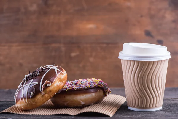 Frische handwerkliche Donuts und Kaffee zum Mitnehmen, hölzerner Hintergrund — Stockfoto