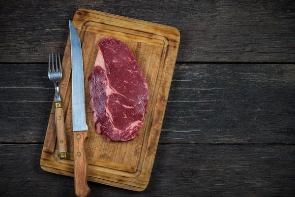 Ruwe ribeye biefstuk overhead op houten rustieke bord — Stockfoto