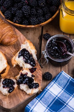 spreading croissant with blackberry jam