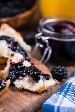 spreading croissant with blackberry jam