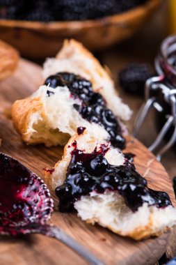 spreading croissant with blackberry jam