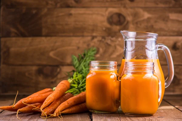 Karottensaft im Einmachglas auf Holzgrund — Stockfoto