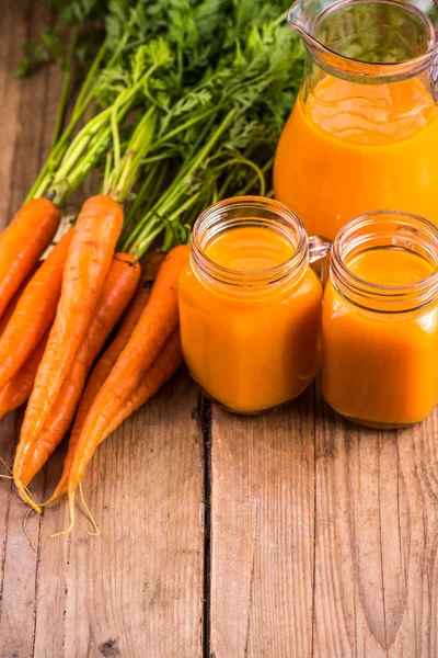 Succo di carota in vaso di muratore su fondo di legno — Foto Stock