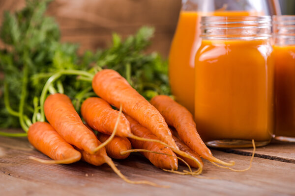 Carrot juice in mason jar on wooden background