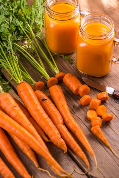 Морковный сок в банке каменщика на деревянном фоне — стоковое фото