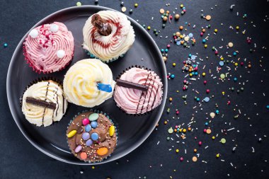 Koyu arka plan üzerinde plaka üzerinde canlı cupcakes