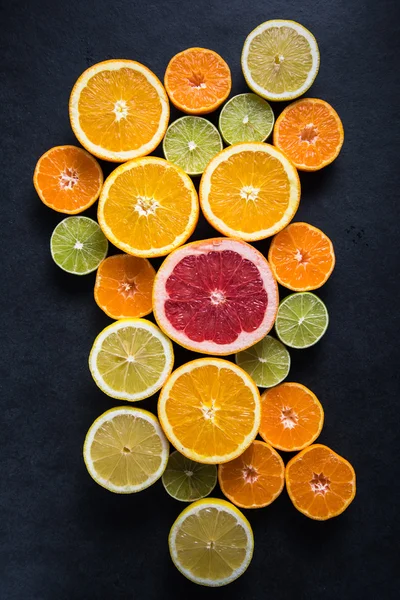 Frutas meio cortadas de citrinos no fundo escuro — Fotografia de Stock