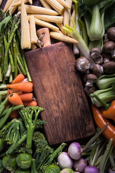 Produtos hortícolas frescos e tábua de corte vazia — Fotografia de Stock