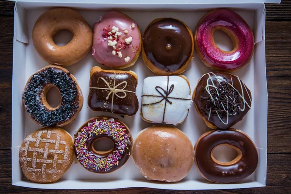 Doze donuts artesanais em caixa na mesa — Fotografia de Stock